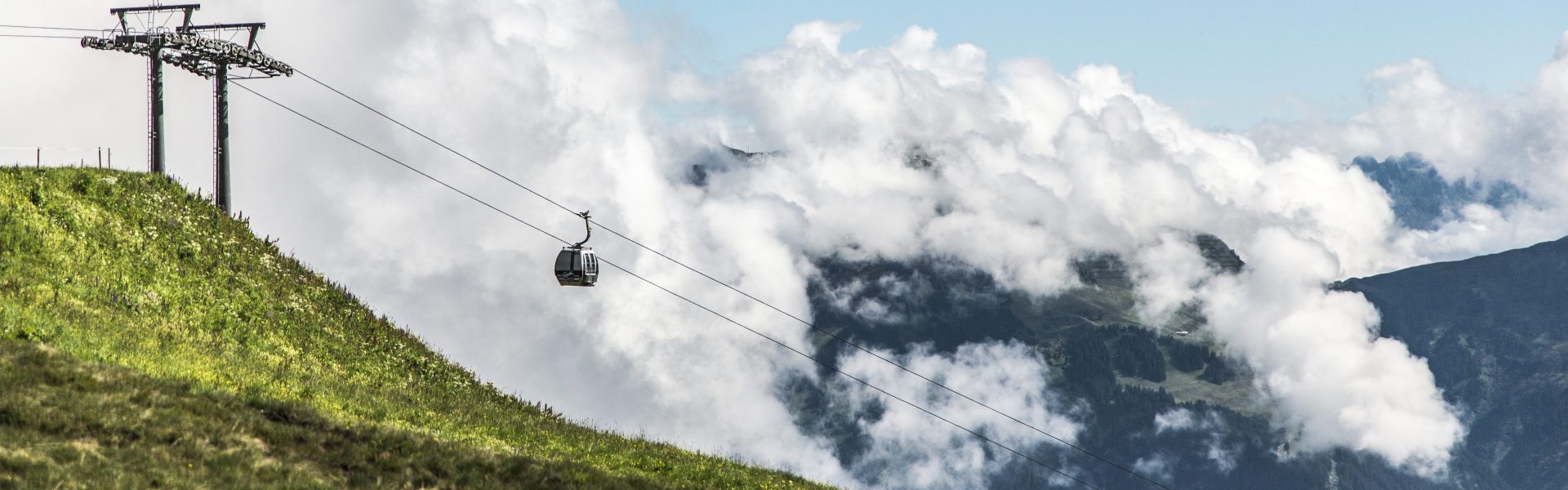 Eine Gondel der Bergbahn, dahinter die Berge und Wolkengebilde am Himmel; V-CARD Ausflugsziel Bergbahnen Gargellen © Christoph Schöch/Bergbahnen Gargellen