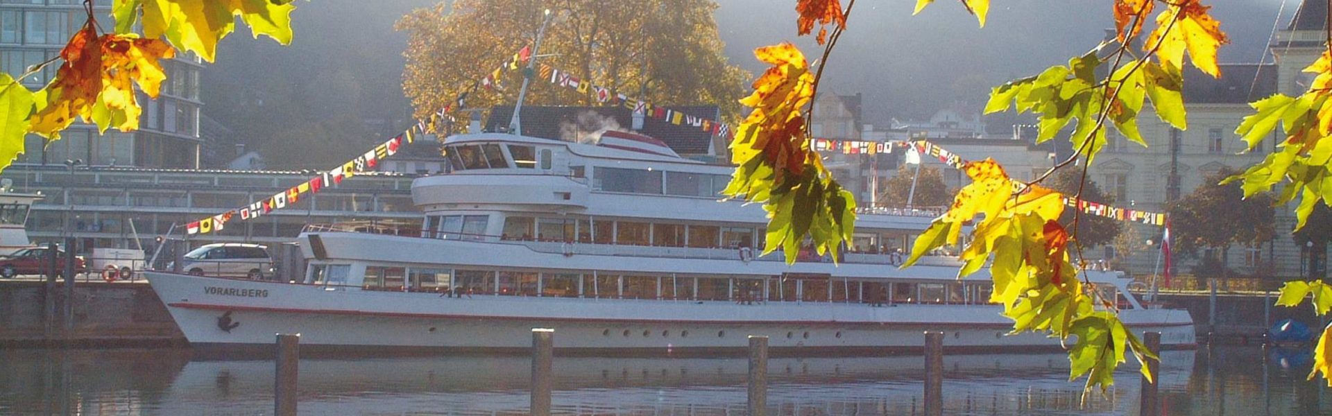 Ein Schiff des V-CARD Bonuspartner Vorarlberg Lines im Hafen von Bregenz, im Vordergrund herbstlich bunt gefärbte Blätter