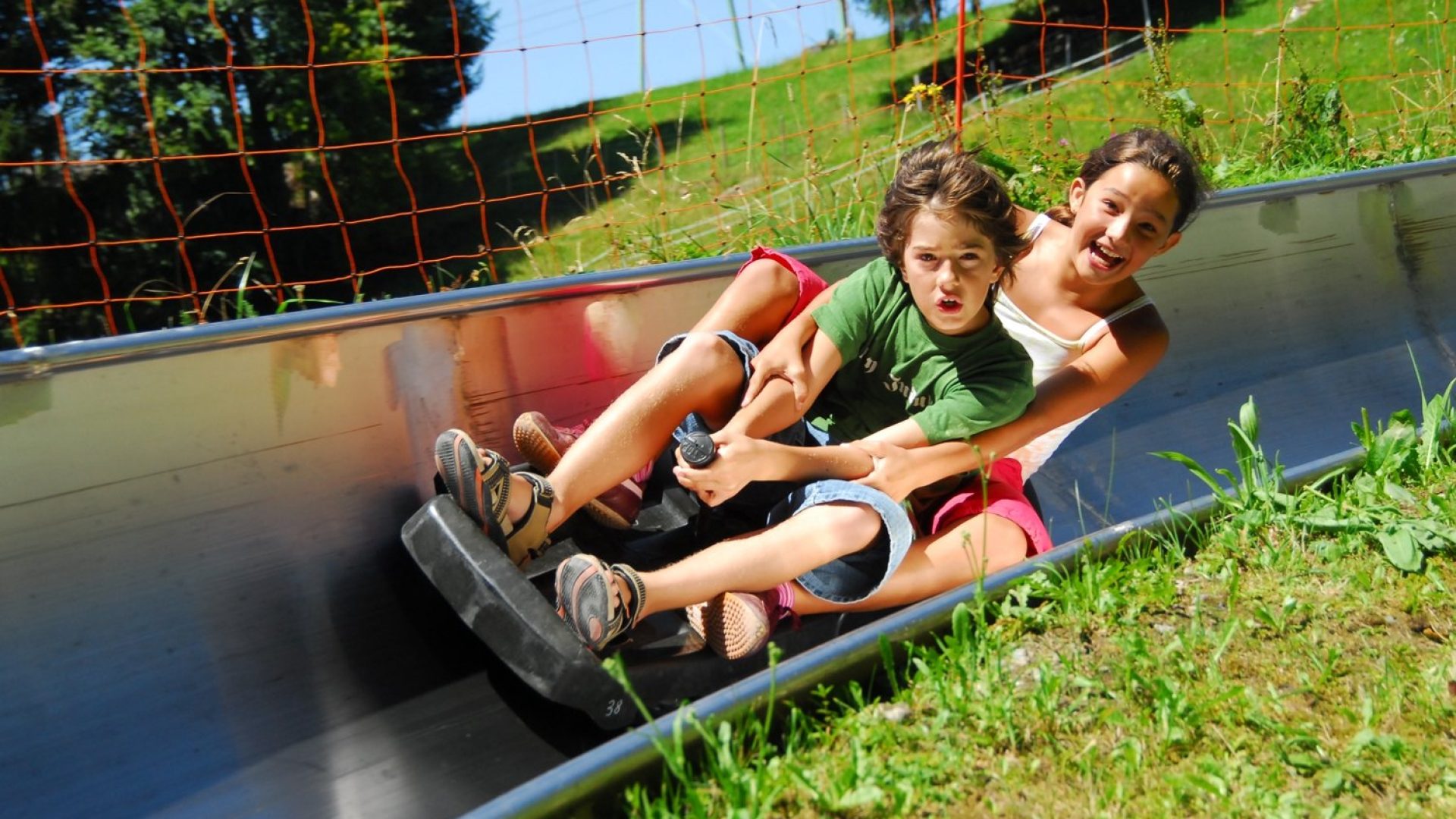Zwei Kinder fahren auf der Sommerrodelbahn in Laterns und haben Spaß.